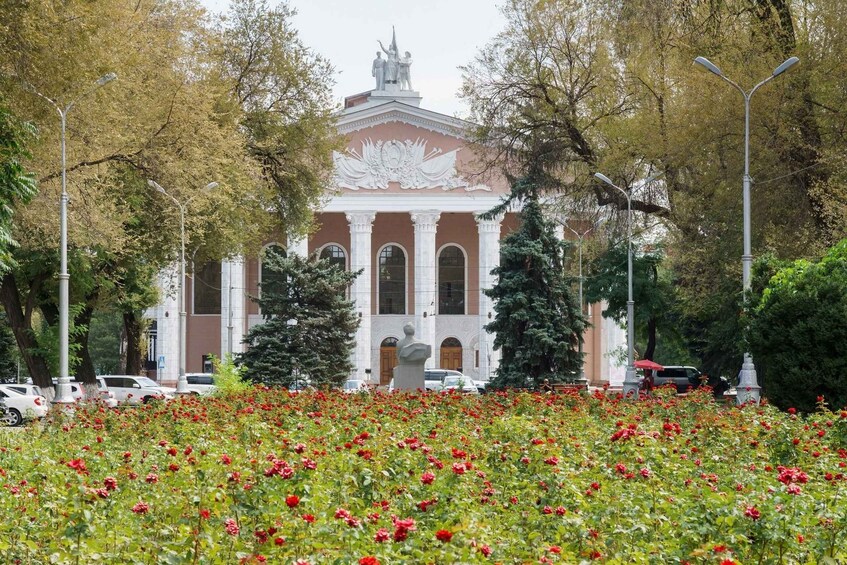 A building with classical architecture, surrounded by a field of red flowers and trees. 2