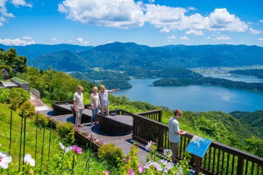 A group of people on a wooden deck overlooking a lake and mountains. 1