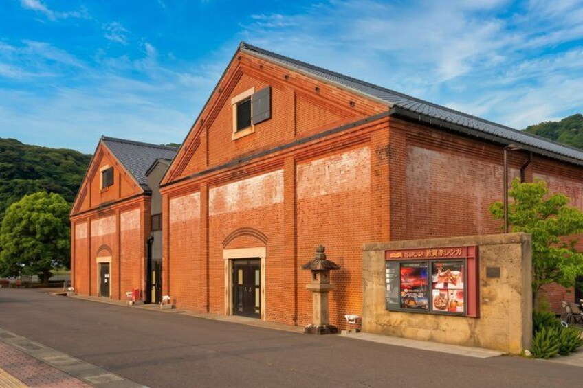 A brick building with a pitched roof, a small attached structure, and a signboard. 2