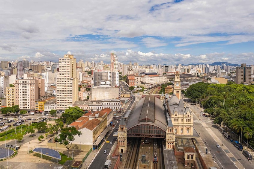 A cityscape with a prominent train station, a clock tower, and a mix of modern and historic buildings. 5