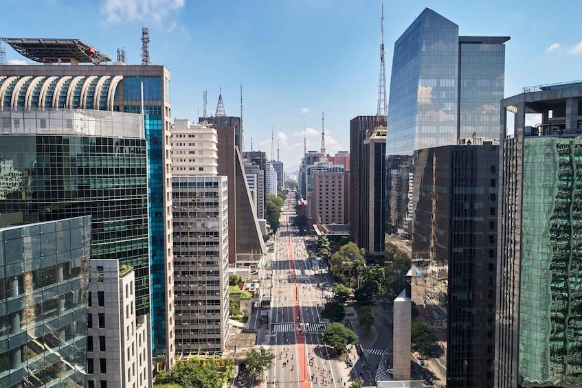 A cityscape with modern high-rise buildings, a clear sky, and a busy street. 2