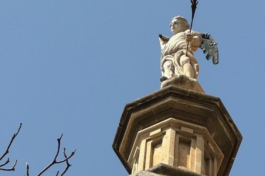 Eine Steinstatue einer Figur, die eine Lanze auf einer sechseckigen Struktur hält. 4