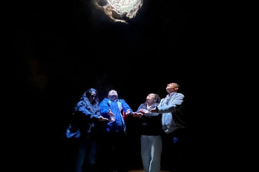 Eine Gruppe von Personen in dunkler Umgebung, möglicherweise einer Höhle oder einem unterirdischen Raum, mit einem Scheinwerfer darüber. 2