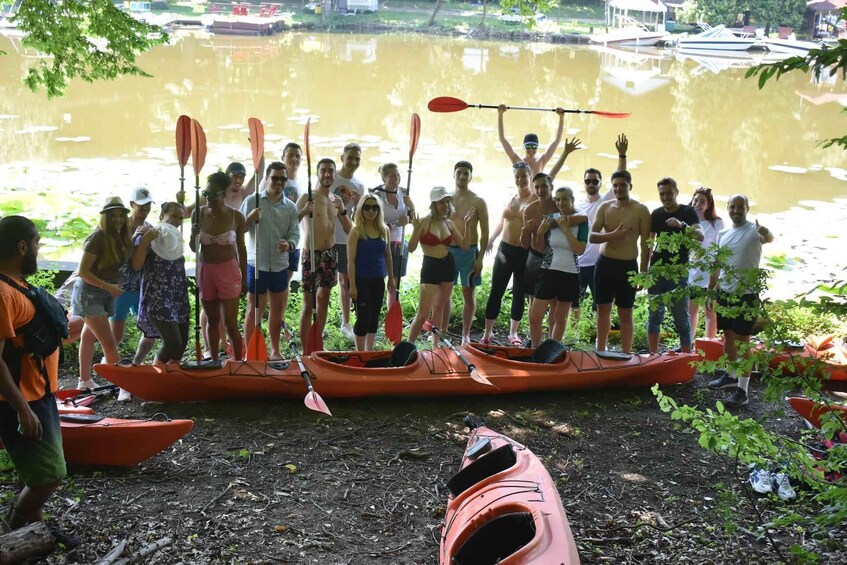 A group of people standing on a dock with kayaks, holding paddles, and preparing for a kayaking activity. 1