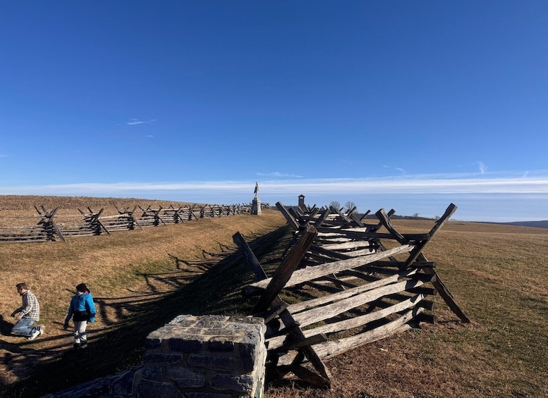 A historical wooden fence with a stone monument in a grassy field. 2