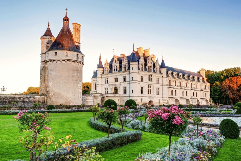 A historic castle with a large tower, manicured gardens, and a formal lawn. 4