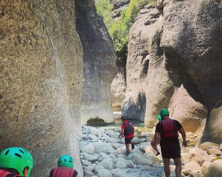 A narrow canyon with rocky terrain and a small stream. 1