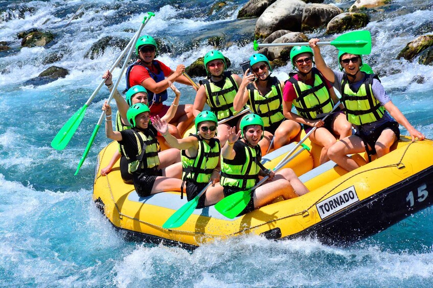A group of people in a yellow inflatable raft labeled 'TORNADO' navigating a river with rapids. 4