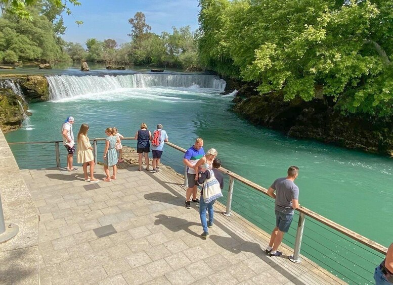 A group of people standing on a stone walkway by a waterfall. 3
