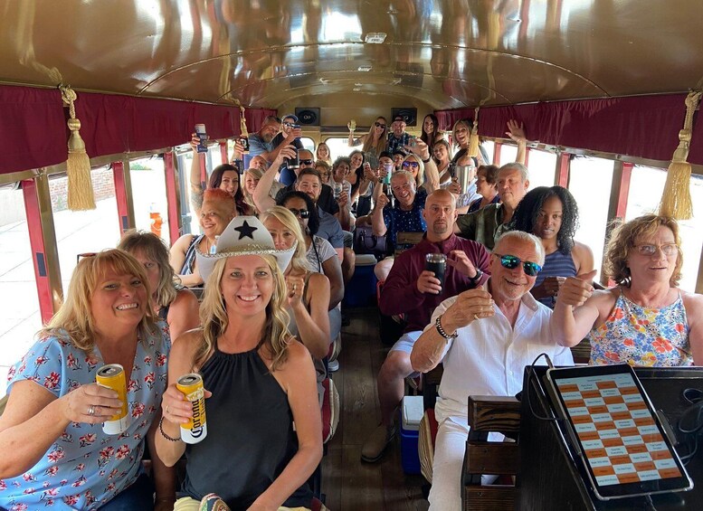 A group of people on a bus, some holding drinks and wearing hats. 5