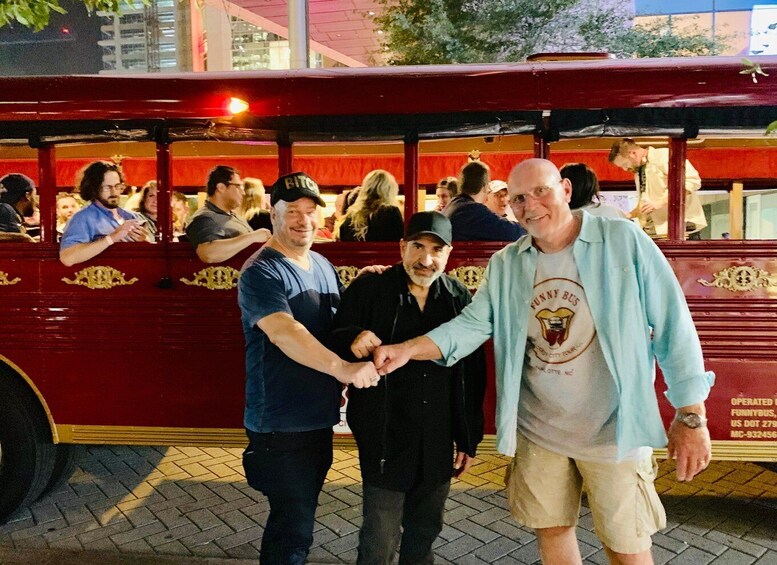 Two men shaking hands in front of a red bus with 'Funny Bus' written on it. 4