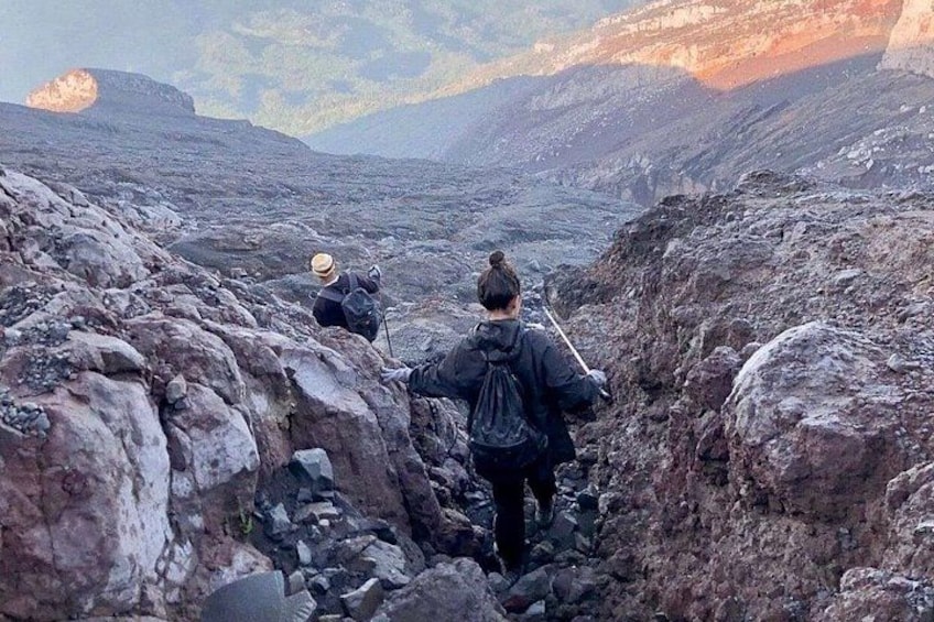 Dos excursionistas transitando un terreno rocoso con montañas al fondo. 5