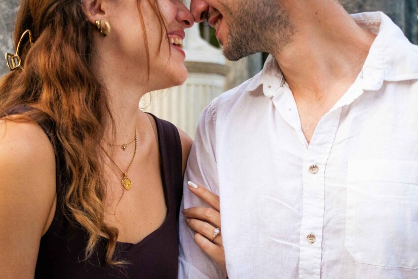 A couple embracing, with the woman wearing a dark top and gold jewelry, and the man in a white shirt. 3