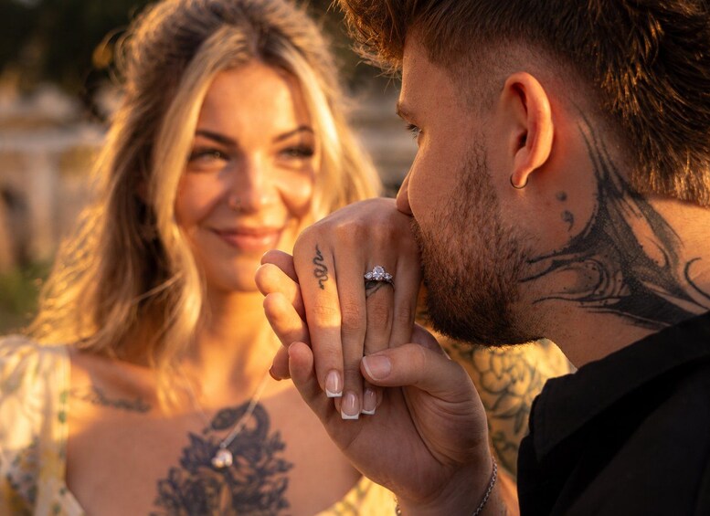 A person holding a ring with a visible tattoo on their hand. 1