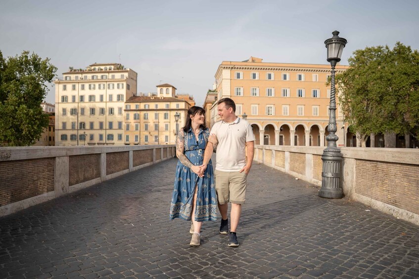 A couple standing on a cobblestone bridge with historic buildings in the background. 4