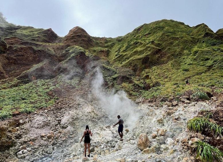 A volcanic landscape with two people walking amidst steam and rocky terrain. 4