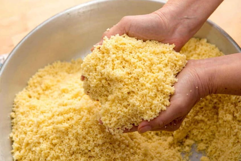 Hände halten eine Schüssel mit Couscous. 5