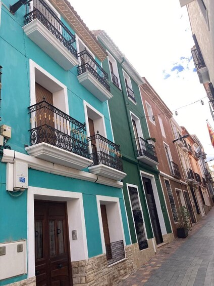 A row of colorful buildings with balconies and a paved street. 4