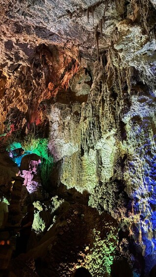 A cave with colorful stalactites and stalagmites illuminated by artificial lighting. 2