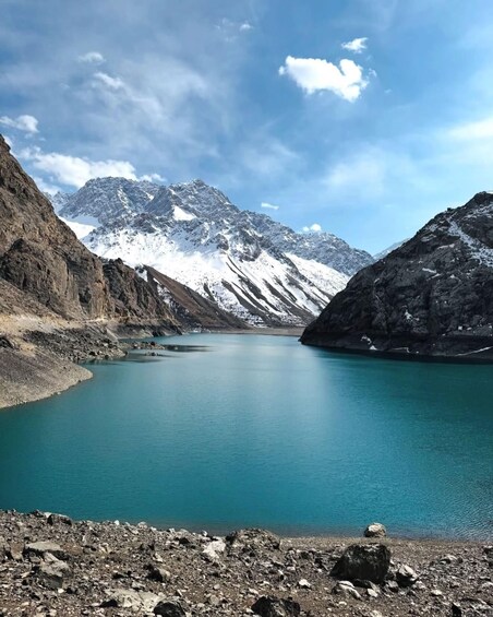 A mountain lake with clear turquoise water, surrounded by rugged mountains and snow-capped peaks. 1