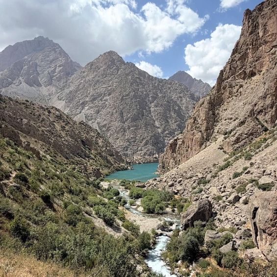 A mountainous landscape with a river flowing through a valley, surrounded by rocky cliffs and sparse vegetation. 3
