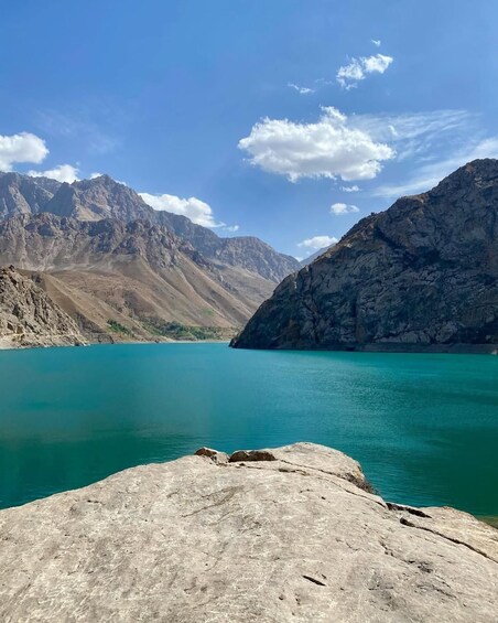 A mountain lake with clear turquoise water, surrounded by rugged mountains under a blue sky. 5