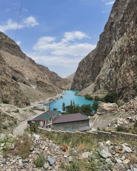 A turquoise lake surrounded by rocky cliffs, with a building in the foreground. 1
