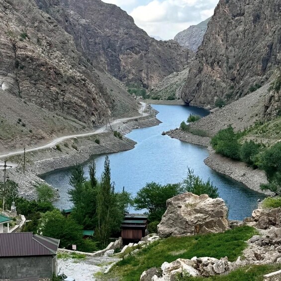 A river winding through a mountainous valley with a road and a small building. 2