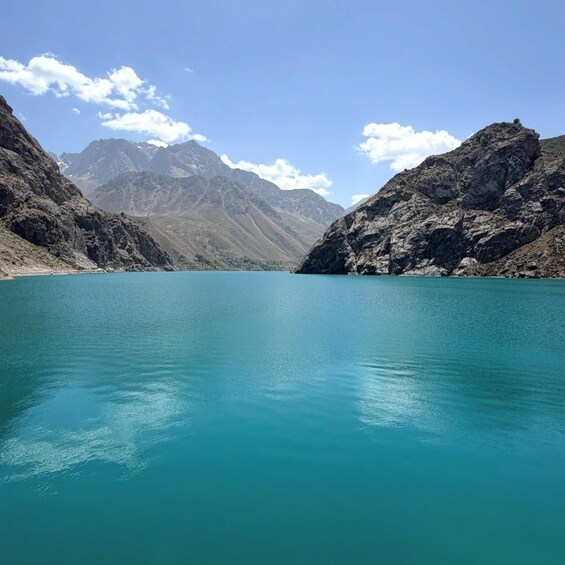 A turquoise lake surrounded by rugged mountains under a clear sky. 2