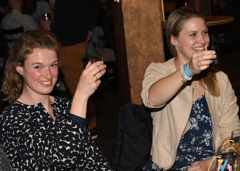 Two people sitting at a table, one holding a drink. 4