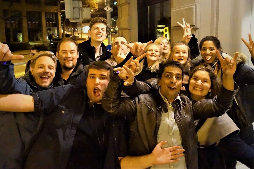 A group of people posing for a photo at night, making peace signs. 3