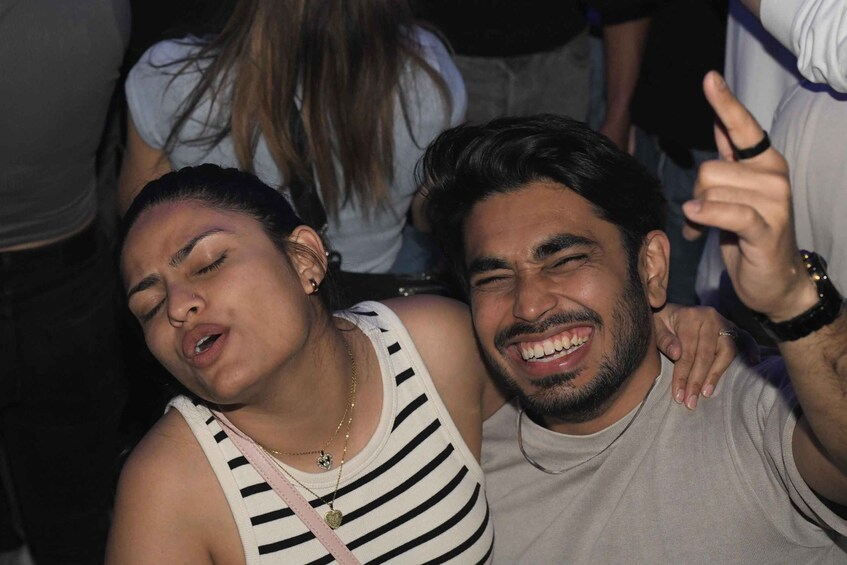 Two people close together, one wearing a striped tank top and the other in a light-colored shirt. 5