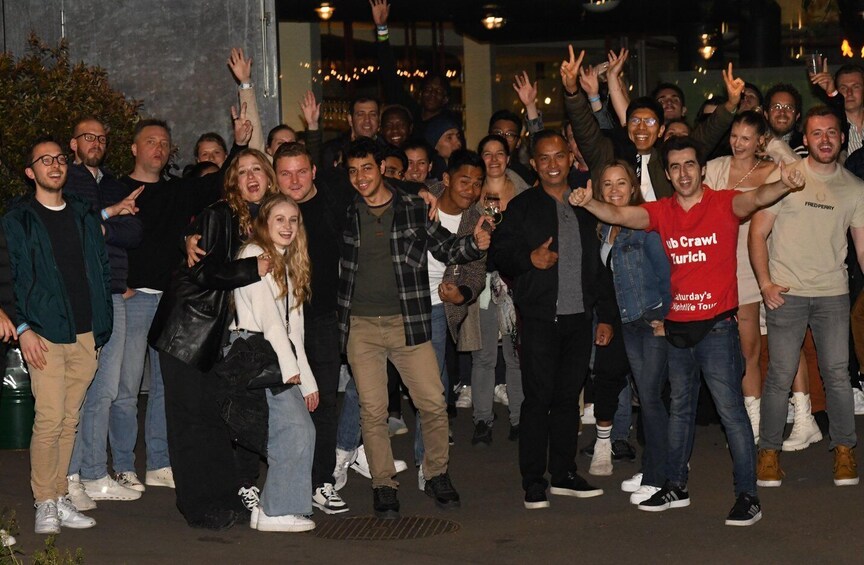 A group of people outdoors at night, some wearing casual clothing and one in a red shirt with text. 2