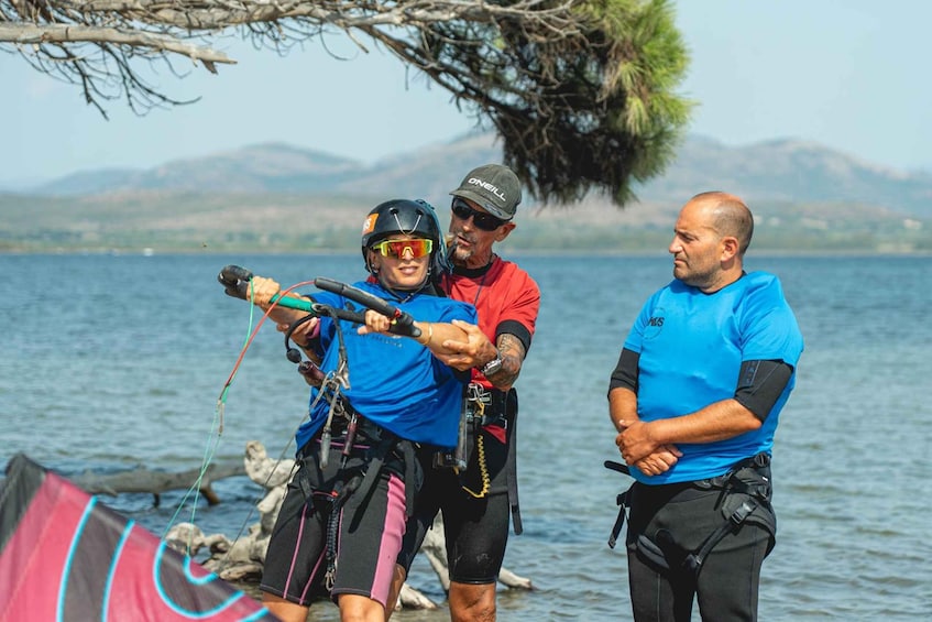 Three people near a lake with a kiteboarder and a man in a red shirt. 2