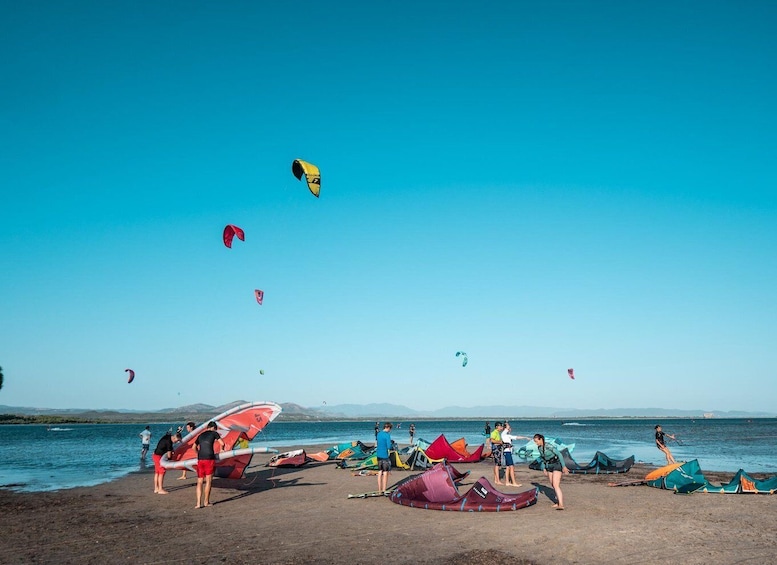 A beach with people preparing kites and windsurfing equipment. 4