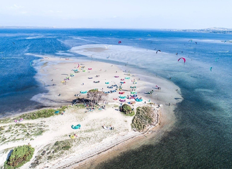 An aerial view of a beach with people engaging in kite surfing and parasailing. 1