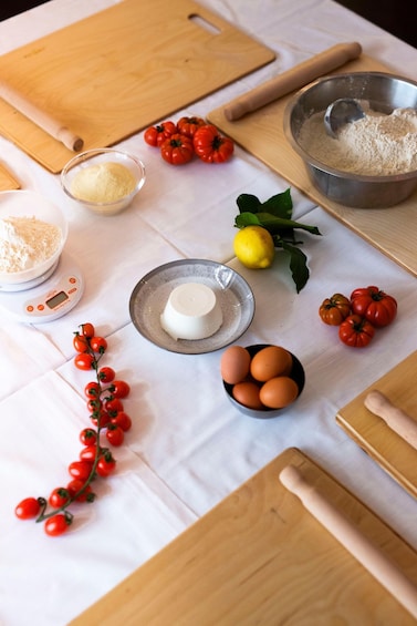 A kitchen counter with ingredients and utensils for baking, including flour, eggs, tomatoes, and a rolling pin. 3