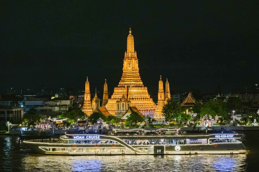 A brightly lit temple complex at night with a boat named 'NOAH CRUISE' in the foreground. 1