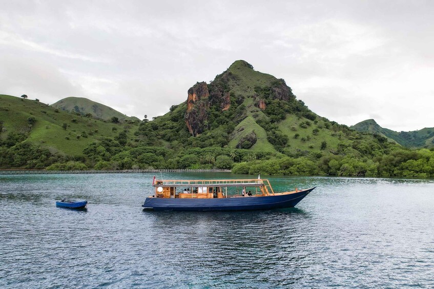 A large boat on calm water with a mountainous landscape in the background. 3