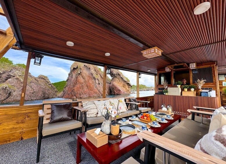 An interior dining area with wooden furniture, a table set for a meal, and a view of rocky cliffs. 2