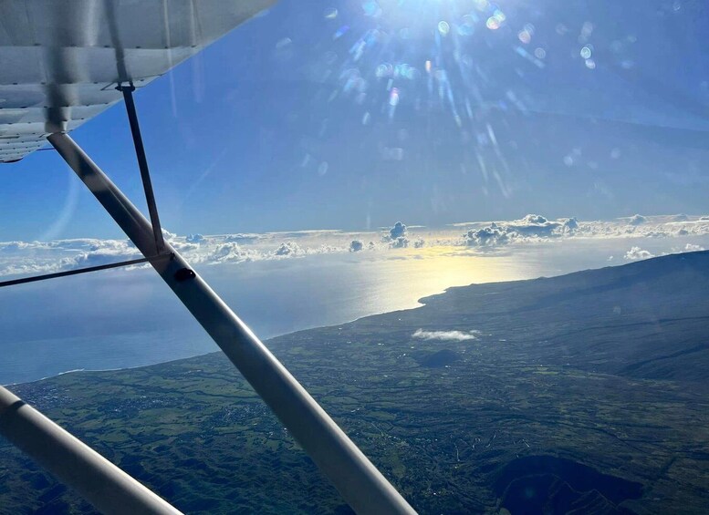 A clear sky with sunlight, clouds, and a landscape below. 1