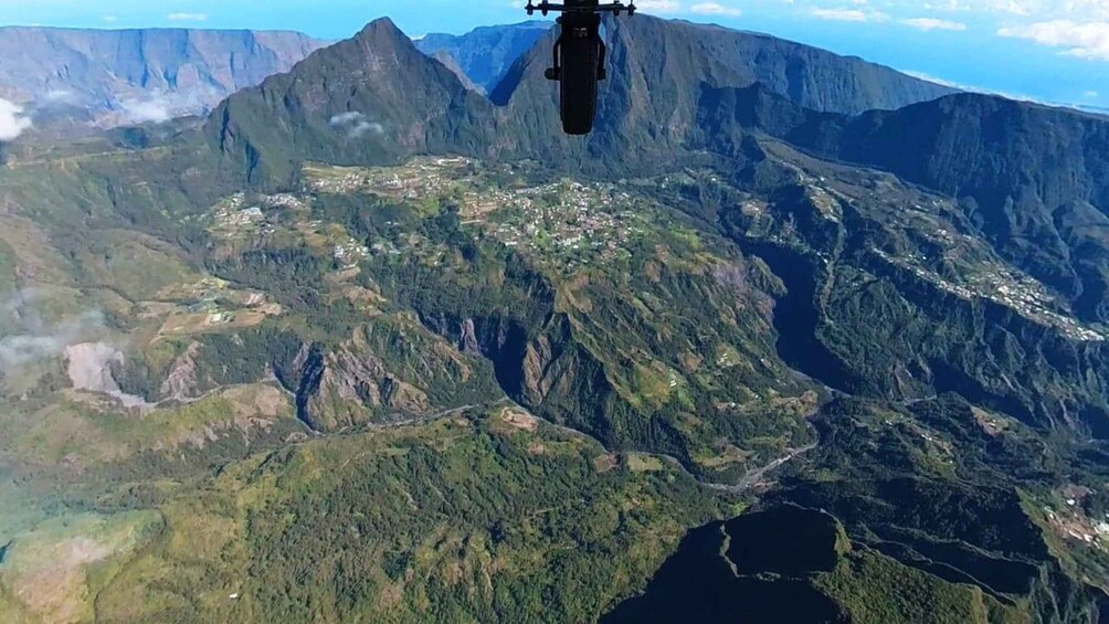 A helicopter flying over a mountainous landscape with visible roads and buildings. 4