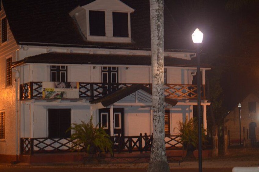 A two-story building with a balcony, a street lamp, and a fence. 1