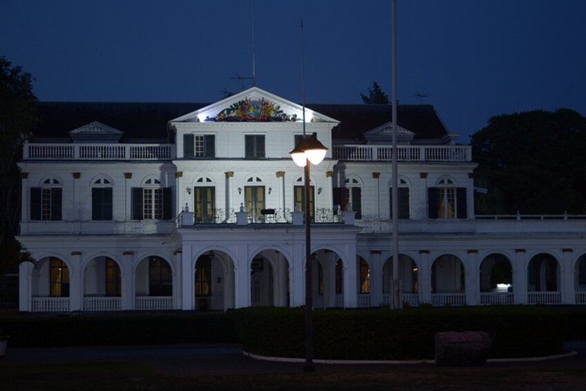 A large white building with arched windows and a balcony, illuminated by street lamps. 3
