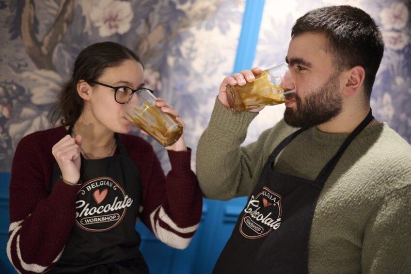 Dos personas con delantales con logotipos de chocolate, una sosteniendo un vaso. 3