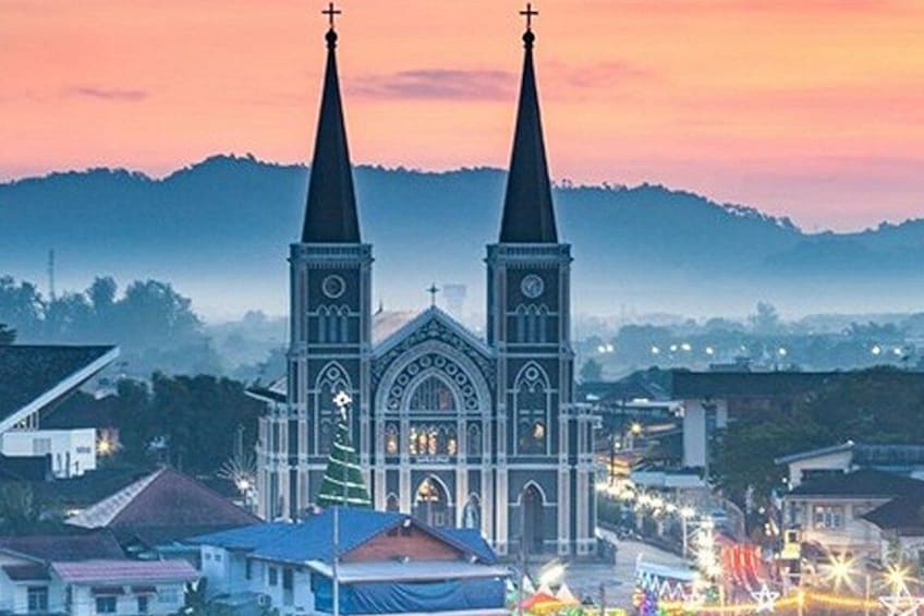 A church with two spires, a clock tower, and a cross at the top. 1