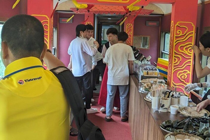 A group of people in a restaurant with red and yellow decor, a counter with food items, and a person in a yellow shirt with a logo. 3