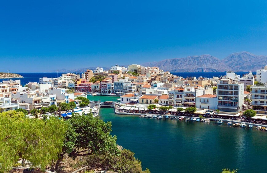 A coastal town with buildings along the waterfront, a marina with boats, and mountains in the background. 4