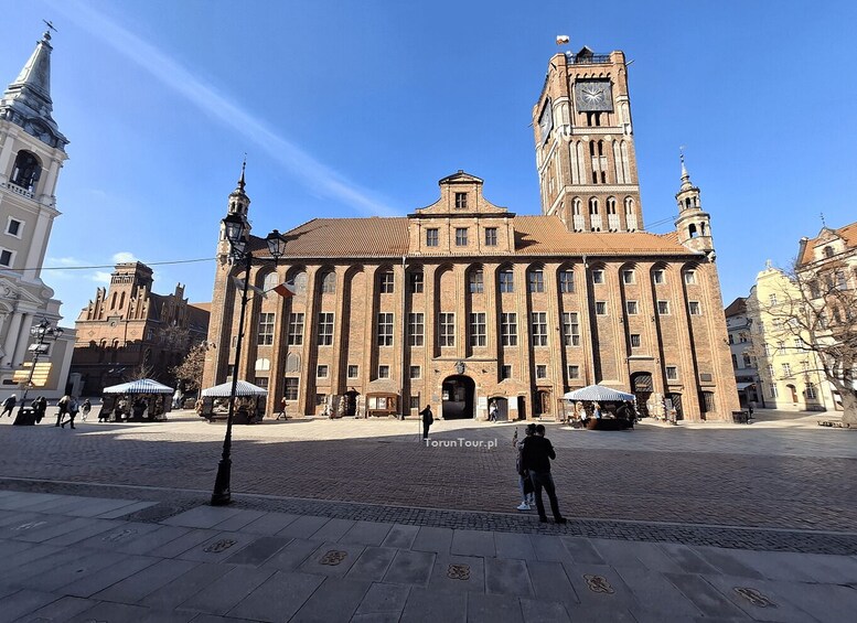 A historic building with a clock tower, cobblestone square, and surrounding architecture. 2