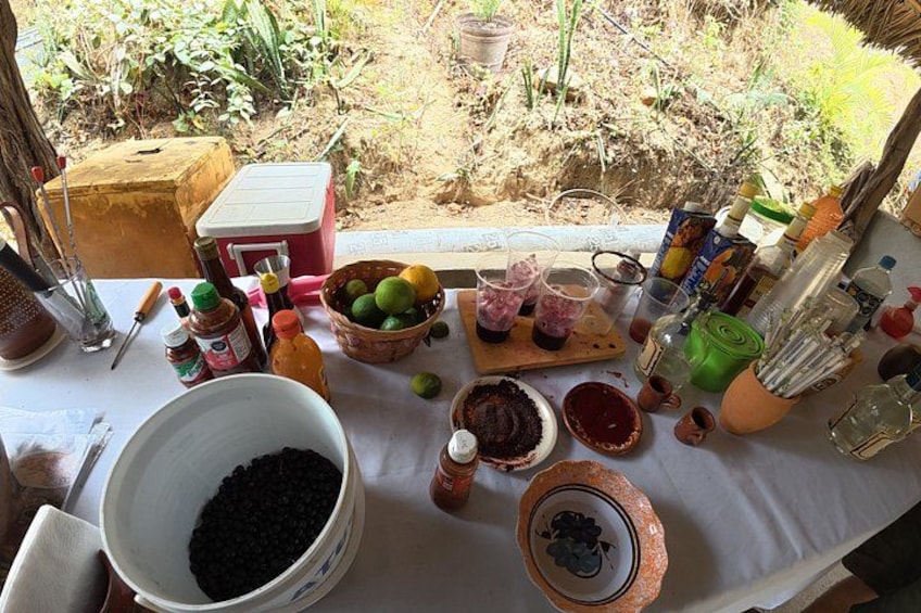 A table with various food items and cooking ingredients, including a large bowl of black beans, a bowl of lime slices, and several bottles of sauces. 5